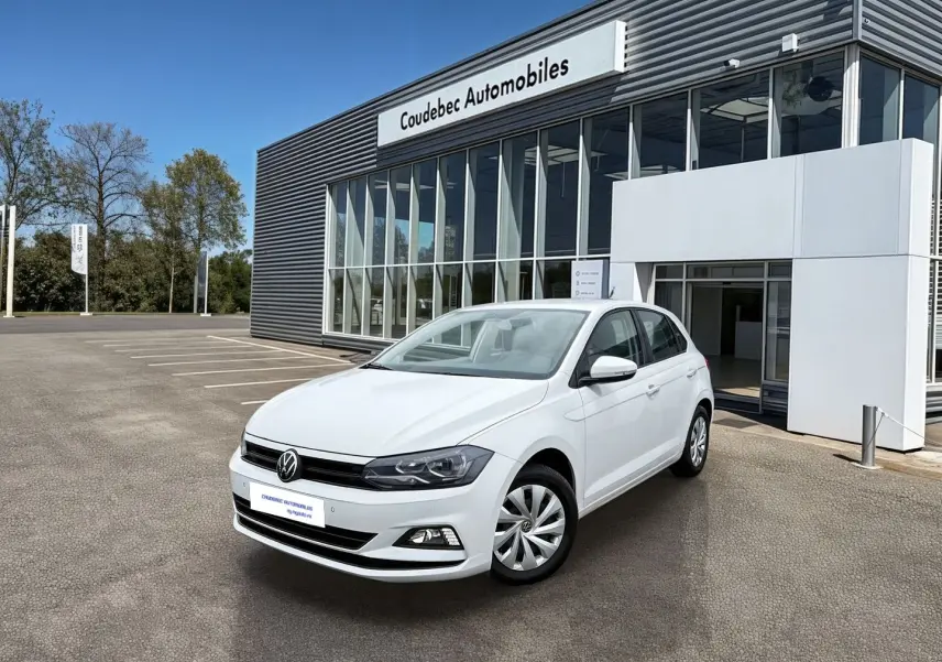 Volkswagen Polo Business blanche vue en 3/4 avant droit devant un bâtiment de concession automobile.