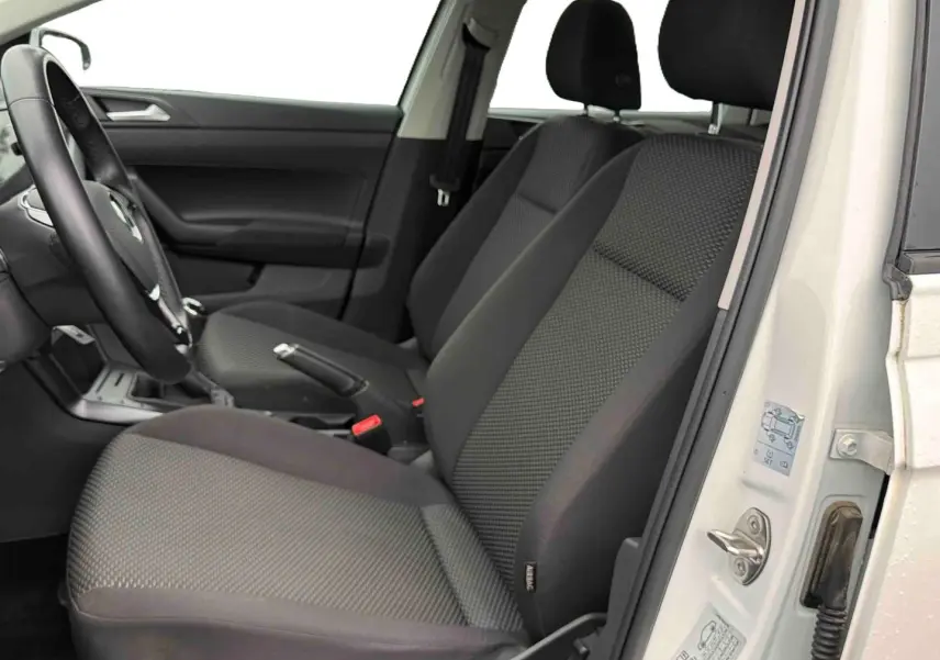 Vue intérieure côté gauche de la Volkswagen Polo Business 2021 blanche, montrant les sièges avant en tissu gris et le volant.