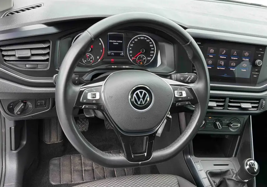 Vue intérieure centrée sur le volant noir de la Volkswagen Polo Business 2021 avec tableau de bord et écran tactile.