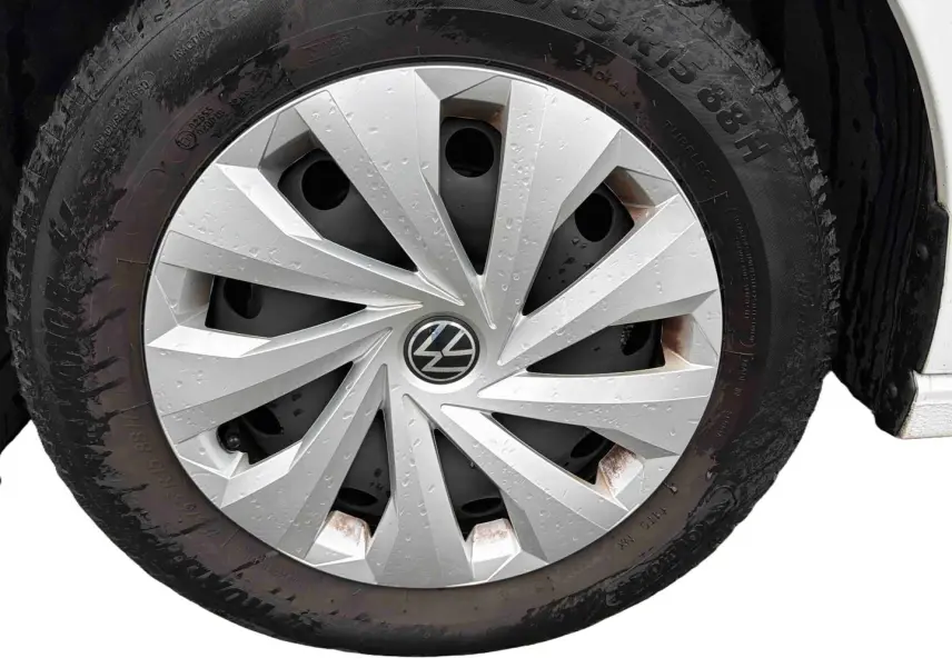 Gros plan sur la roue avant droite d'une Volkswagen Polo Business blanche avec enjoliveur en acier argenté et traces de rouille.