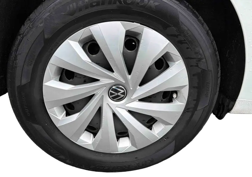 Gros plan sur la roue avant droite blanche d'une Volkswagen Polo Business 2021 avec enjoliveur argenté et logo VW central.