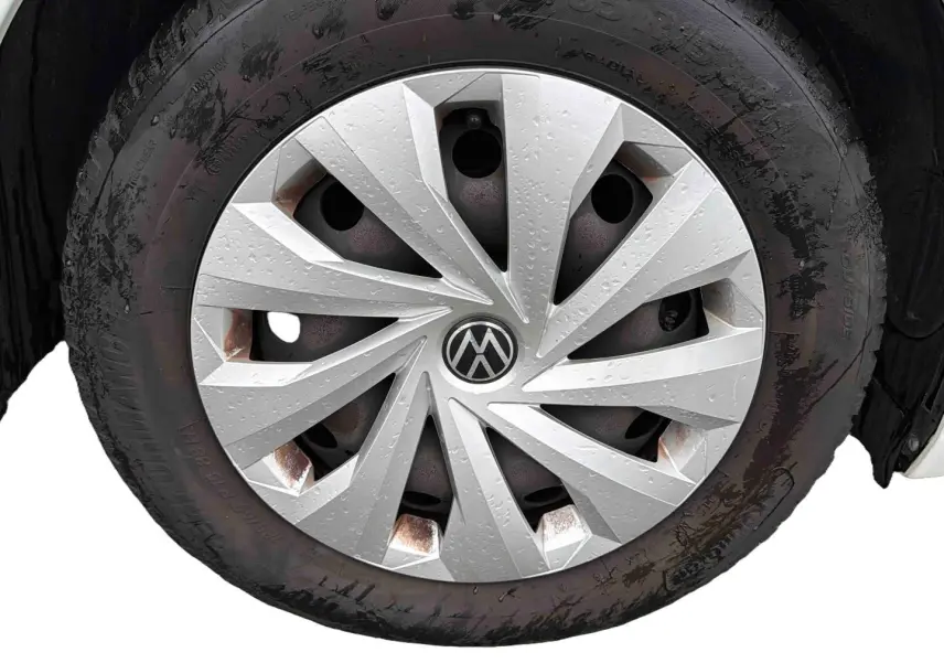 Gros plan sur la roue avant droite d’une Volkswagen Polo Business blanche avec enjoliveur argenté et traces d’humidité.