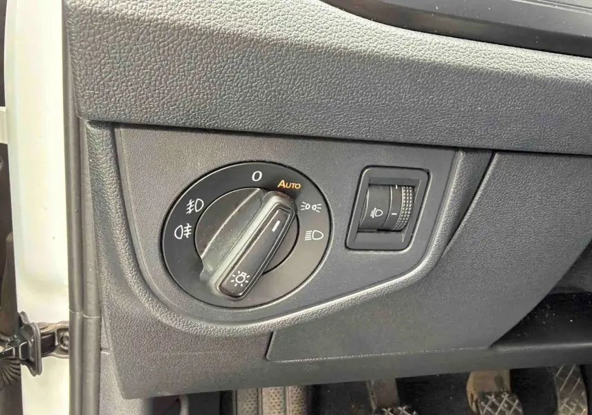 Gros plan sur le sélecteur d'éclairage et le réglage de hauteur des phares dans une Volkswagen Polo Business blanche de 2021.