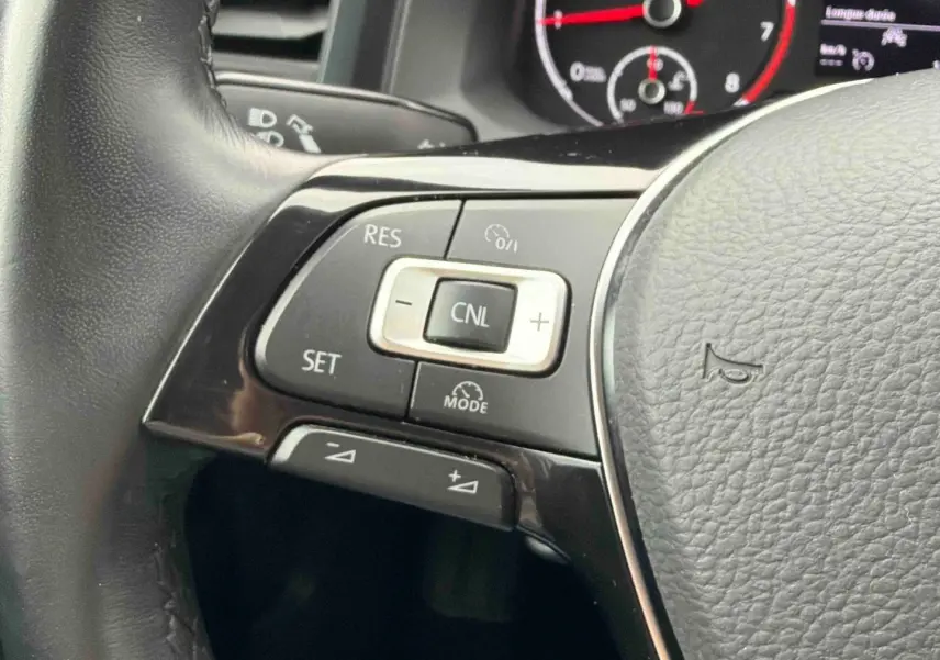 Gros plan sur les commandes du régulateur de vitesse au volant cuir noir de la Volkswagen Polo Business 2021.