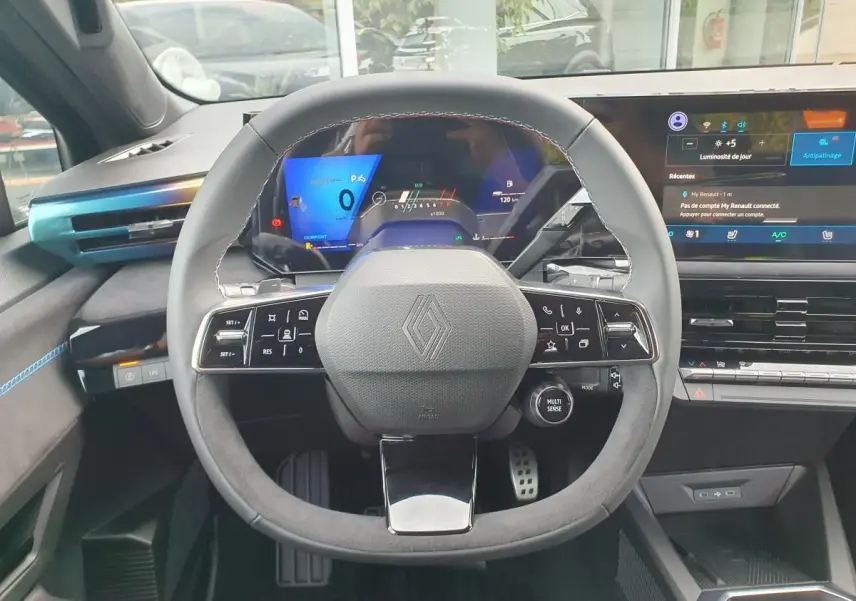 Vue intérieure centrée sur le volant multifonction de la Renault Clio VI avec tableau de bord numérique et écran tactile.