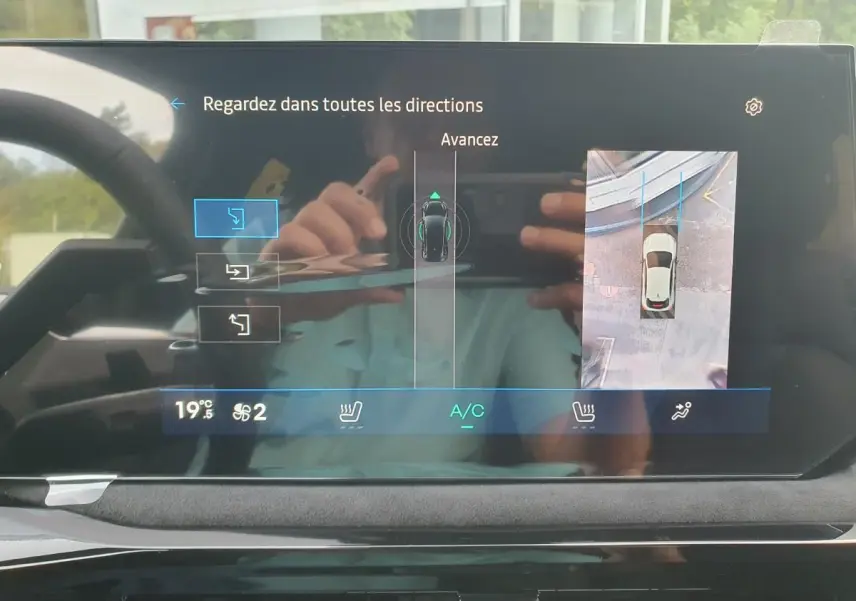 Écran tactile intérieur montrant l’aide au parking avec vue 360° et caméra de recul de la Renault Clio VI noire étoile.