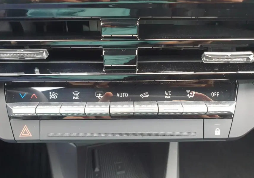 Vue rapprochée du tableau de bord noir de la Renault Clio VI montrant les commandes de climatisation et sécurité.