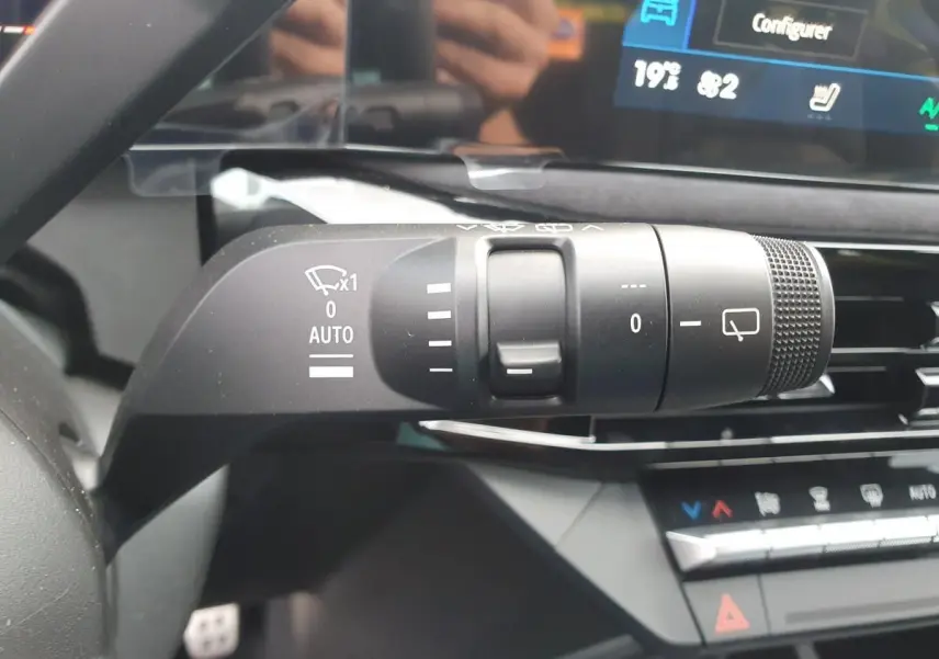 Gros plan sur la commande des essuie-glaces à gauche du volant dans l’habitacle de la Renault Clio VI noire étoile.