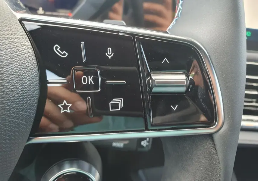 Gros plan sur les commandes multifonctions à droite du volant de la Renault Clio VI noire étoile, avec molette et boutons tactiles.
