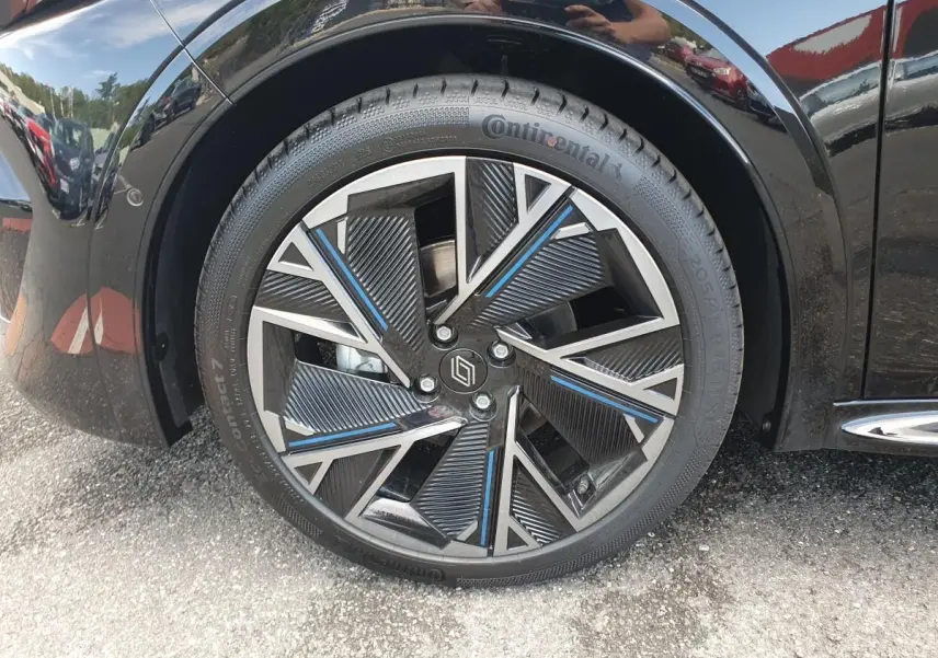 Gros plan sur la jante alliage diamantée 18” cosmic noire et argent avec touches bleues de la Renault Clio VI noire étoile.