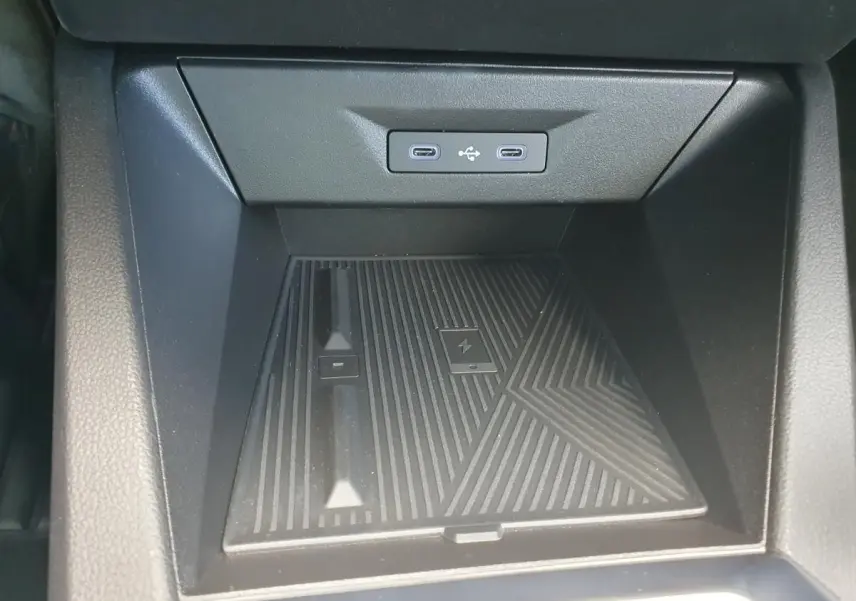 Vue rapprochée du rangement central avant de la Renault Clio VI noire étoile, avec deux prises USB-C et chargeur sans fil intégré.