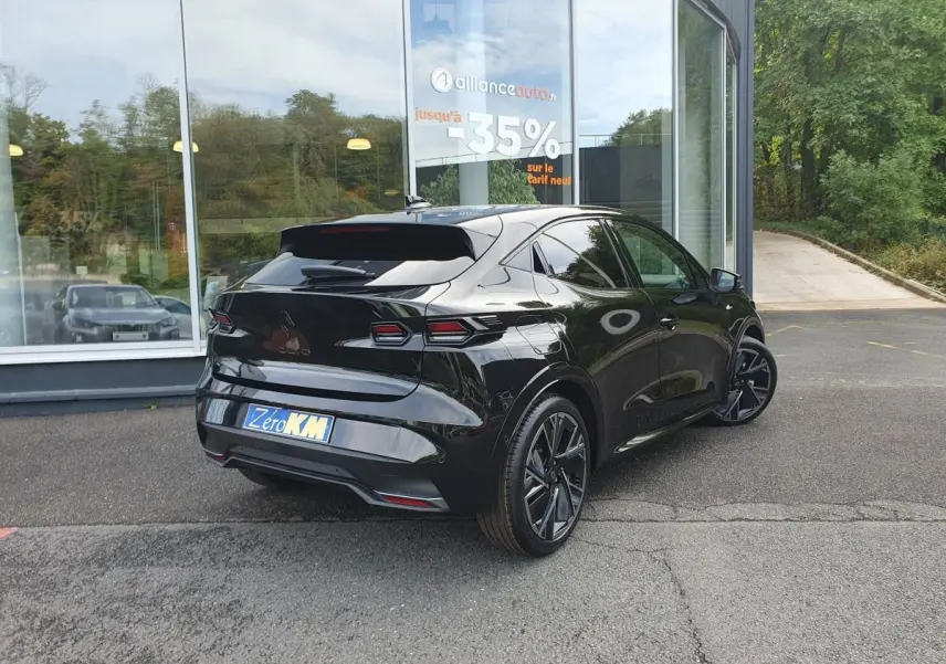 Vue 3/4 arrière droite d’une Renault Clio VI noire étoile avec jantes alliage 18” cosmic et vitres surteintées.
