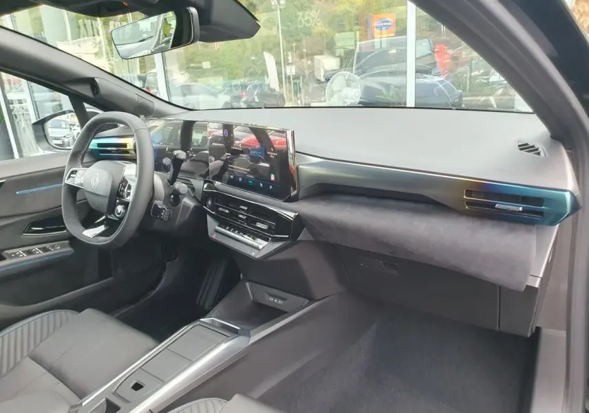 Intérieur avant de la Renault Clio VI noire étoile, vue côté passager avec tableau de bord moderne et écran tactile central.