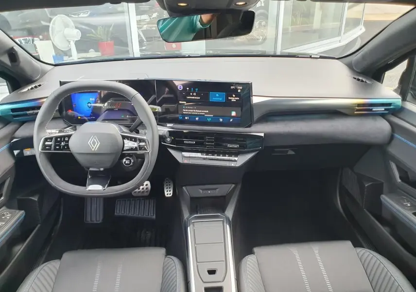 Vue intérieure avant du tableau de bord et volant de la Renault Clio VI noire étoile avec écran tactile panoramique et finitions bleues.