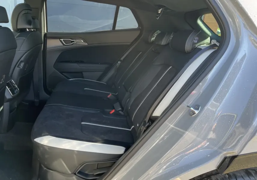 Vue côté gauche de l’habitacle arrière du Kia Sportage gris céramique, sièges noirs avec surpiqûres blanches.