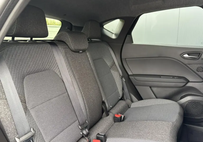 Vue intérieure côté droit sur la banquette arrière grise du Renault Captur 2025 avec appuis-têtes et ceintures visibles.