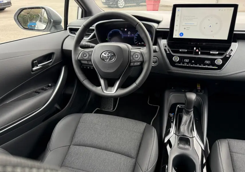 Vue intérieure avant centrée sur le volant et la console centrale d'une Toyota Corolla Touring Sport 2025, finition Active Plus.