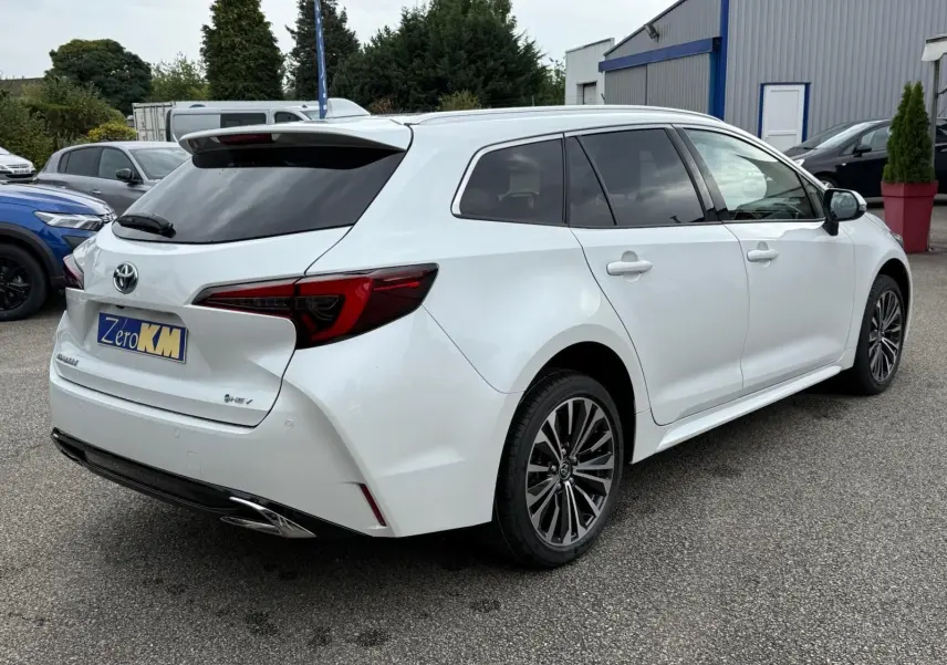 Toyota Corolla Touring Sport blanche nacrée vue de trois quarts arrière droit, avec jantes alliage et feux arrière LED distinctifs.