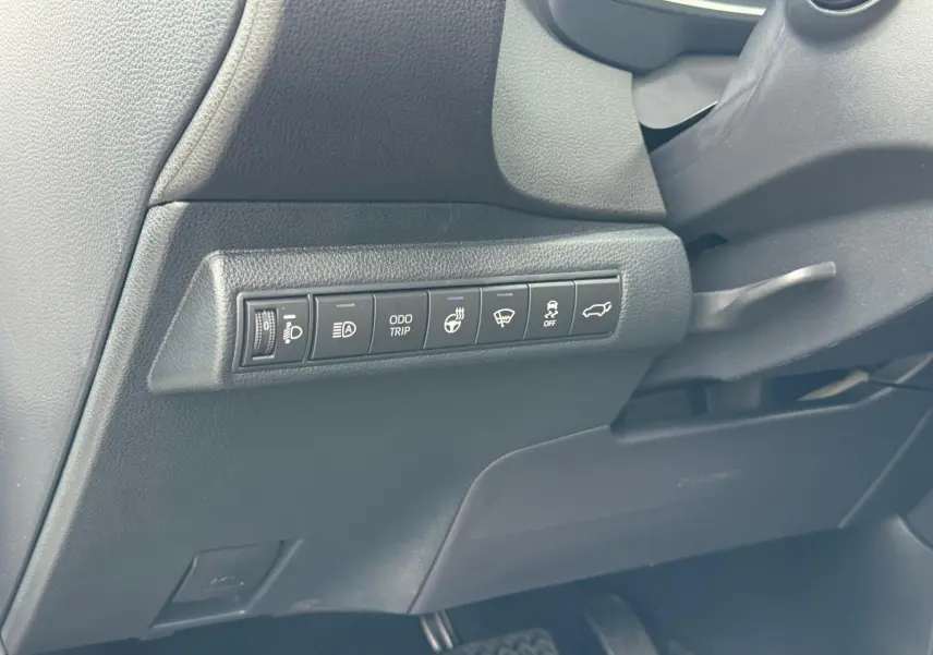 Panneau de commandes latéral noir avec boutons de réglages et fonctions sur le côté gauche du tableau de bord Toyota Corolla Touring Sport 2025.