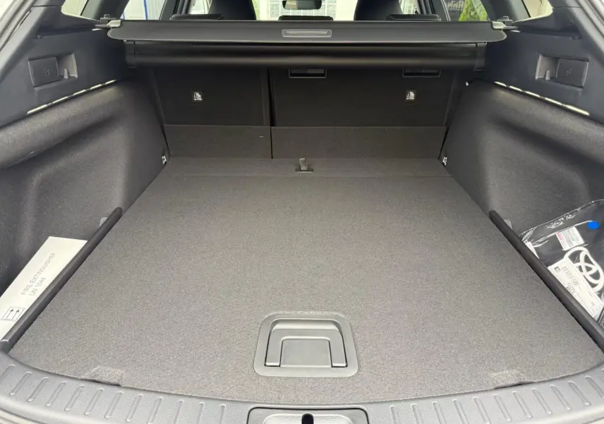 Coffre spacieux de la Toyota Corolla Touring Sport blanc lunaire nacré, vue arrière avec cache-bagages déployé.