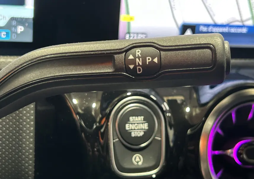 Gros plan sur la commande de boîte automatique et le bouton start/stop du tableau de bord d'une Mercedes CLA Shooting Brake noir métallisé.