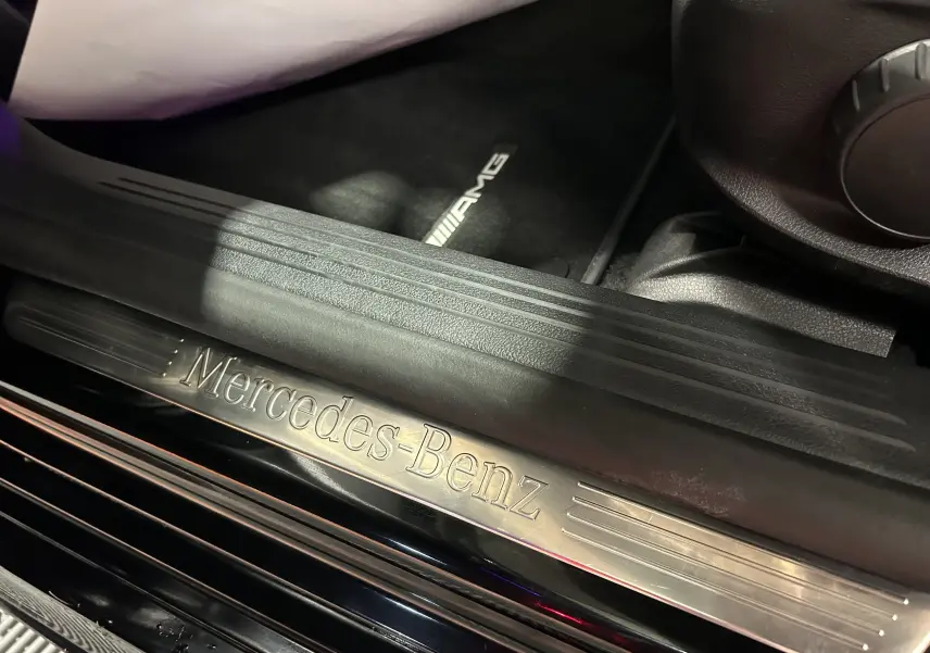 Gros plan sur la plaque de seuil de porte Mercedes-Benz et tapis AMG noir à l'intérieur du CLA Shooting Brake noir métallisé.