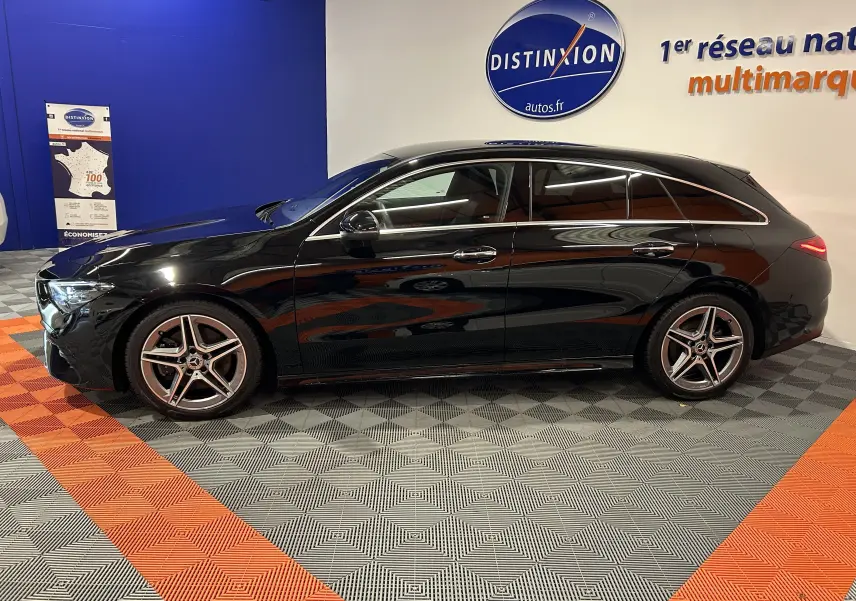 Profil côté gauche d'une Mercedes Classe CLA Shooting Brake II 200D AMG noir métallisé, en intérieur showroom.
