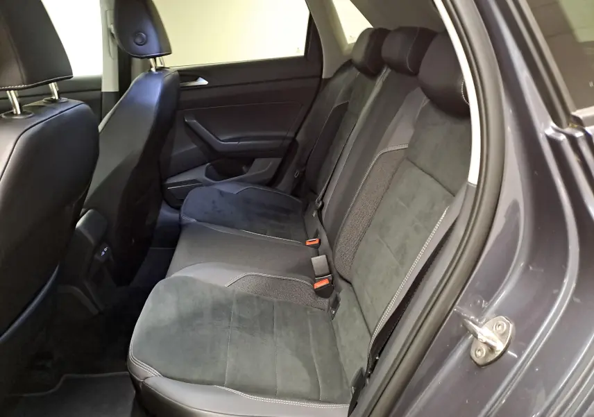 Vue intérieure côté droit des sièges arrière en tissu et cuir gris d'une Volkswagen Polo 2023 gris cendré avec vitres arrière surteintées.