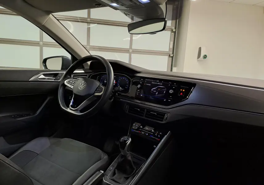 Vue intérieure côté conducteur de la Volkswagen Polo 2023 gris cendré, avec tableau de bord digital et boîte manuelle.