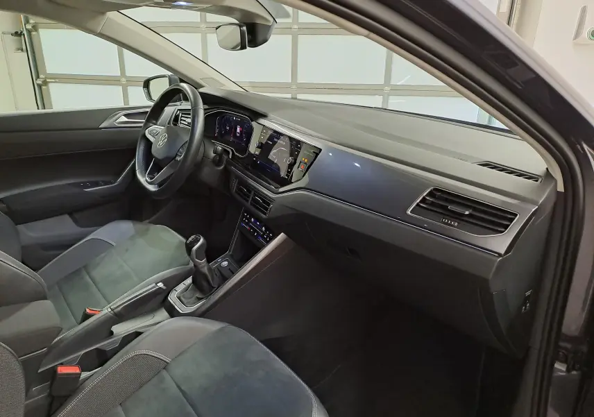 Vue intérieure côté conducteur de la Volkswagen Polo gris cendré 2023, avec tableau de bord digital et boîte manuelle.