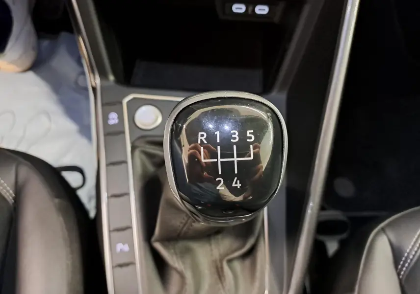 Gros plan sur le levier de vitesses manuel noir de la Volkswagen Polo 2023, intérieur avec coutures blanches visibles.