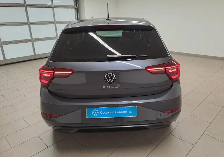 Vue arrière d'une Volkswagen Polo 2023 gris cendré avec vitres arrière surteintées et feux LED allumés dans un garage.