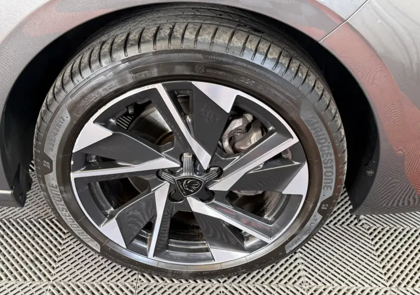 Gros plan sur la roue avant droite de la Peugeot 308 gris foncé, avec jante alliage au design moderne bicolore.