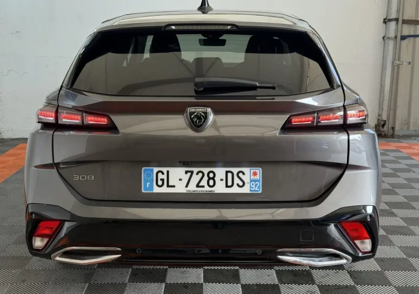 Vue arrière d'une Peugeot 308 gris foncé avec feux LED allumés et double sortie d'échappement chromée.