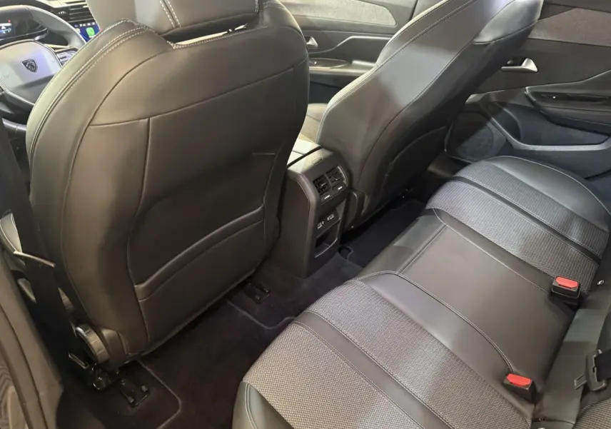 Vue intérieure arrière de la Peugeot 308 gris foncé, montrant les sièges en cuir et tissu et la console centrale avec aérateurs.