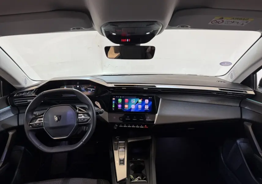 Vue intérieure avant du tableau de bord de la Peugeot 308 2022, avec écran tactile central et volant multifonctions cuir.