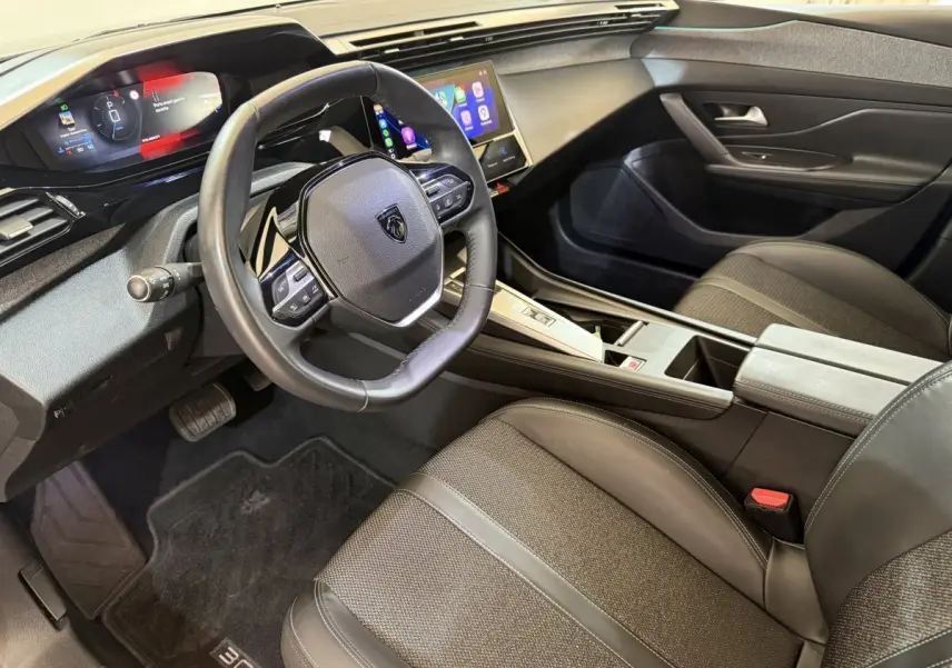Vue intérieure côté conducteur de la Peugeot 308 gris foncé, avec tableau de bord digital et écran tactile central.
