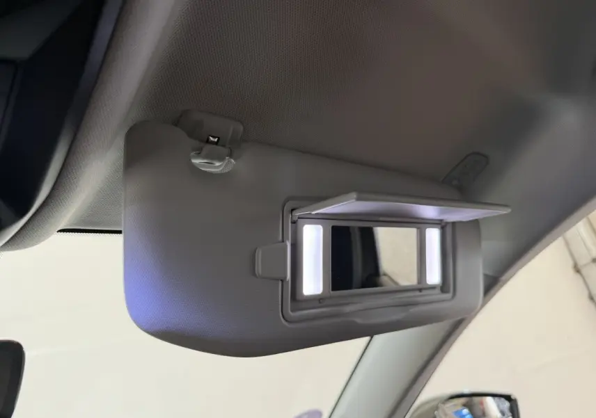 Détail du pare-soleil côté conducteur avec miroir éclairé dans l’habitacle gris clair d’une Peugeot 308 SW 2022.