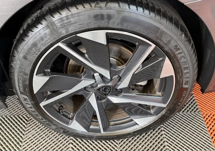Gros plan sur la jante alliage bicolore noire et argentée de la Peugeot 308 SW gris foncé, pneu Michelin visible.