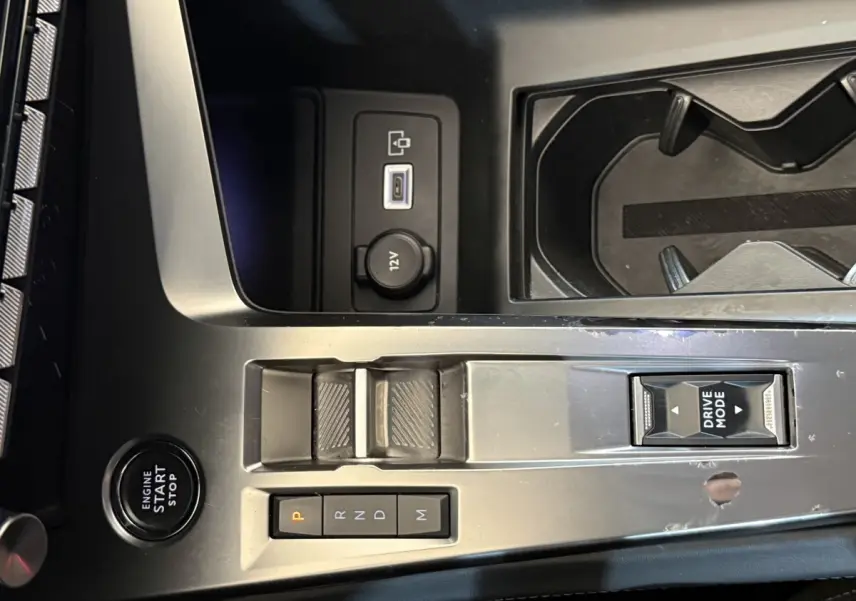 Vue rapprochée de la console centrale grise foncé de la Peugeot 308 avec boutons de boîte auto et bouton Drive Mode.