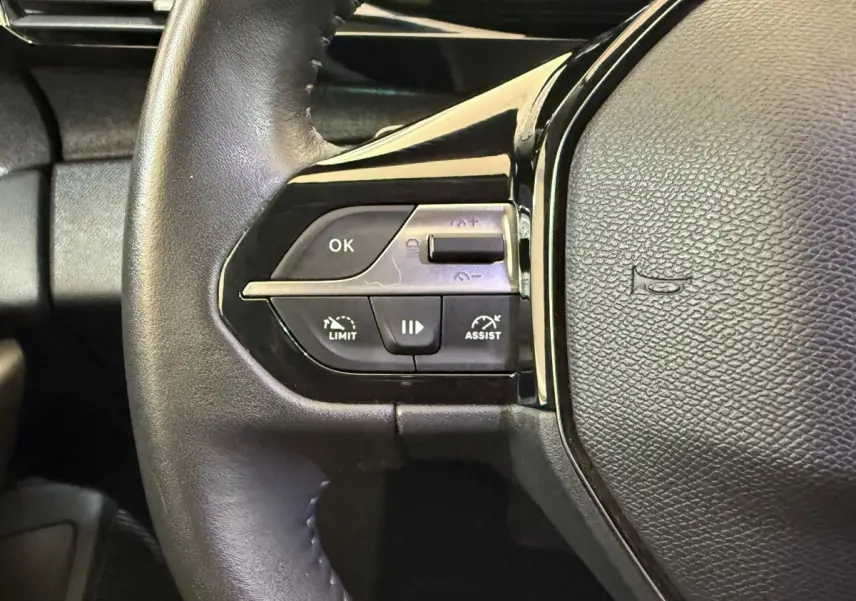 Gros plan sur les commandes de régulateur de vitesse et assistance au volant cuir noir du Peugeot 308 gris foncé 2022.