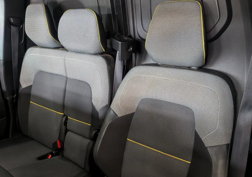Vue rapprochée des sièges avant en tissu gris avec surpiqûres jaunes du Renault Kangoo Van 2021 blanc minéral.
