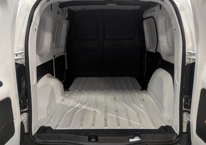 Vue intérieure arrière du Renault Kangoo Van blanc minéral, montrant l'espace de chargement vide et les portes ouvertes.