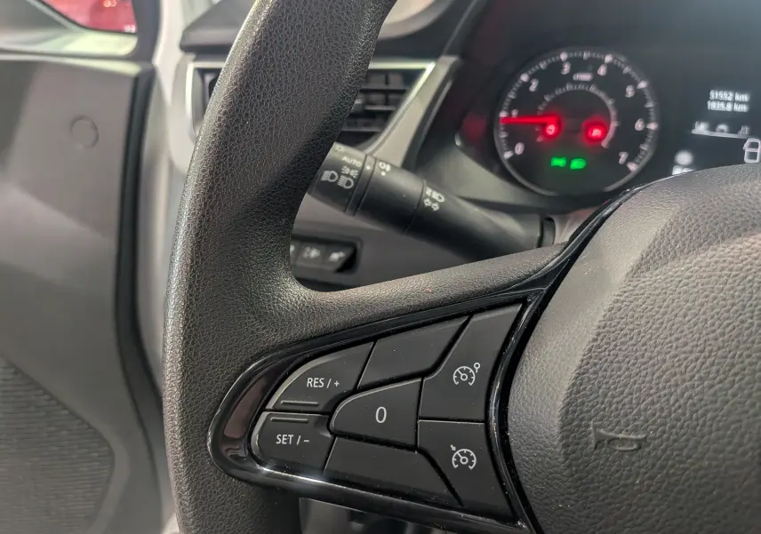 Gros plan sur le volant noir du Renault Kangoo 2021, montrant les commandes de régulateur de vitesse côté gauche.