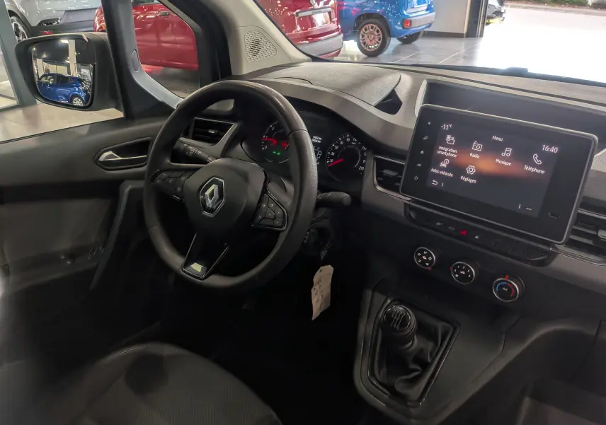 Vue intérieure côté conducteur du Renault Kangoo 2021, tableau de bord noir avec écran tactile et levier de vitesses manuel.