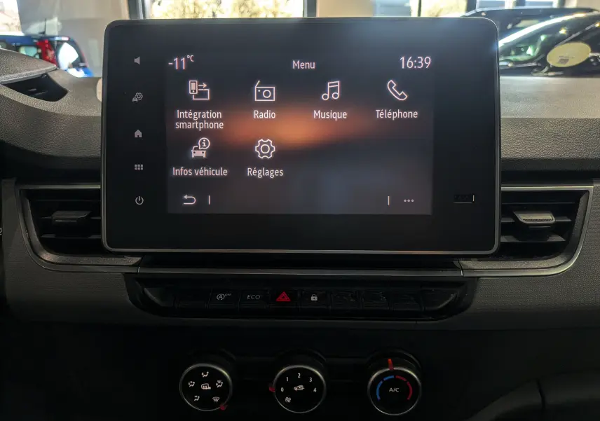 Écran tactile central du tableau de bord du Renault Kangoo blanc, affichant le menu multimédia avec commandes climatisation en dessous.
