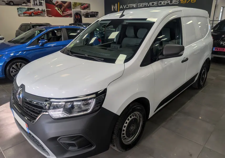 Vue 3/4 avant droit d’un Renault Kangoo Van blanc minéral avec pare-chocs noir mat et jantes acier en showroom.