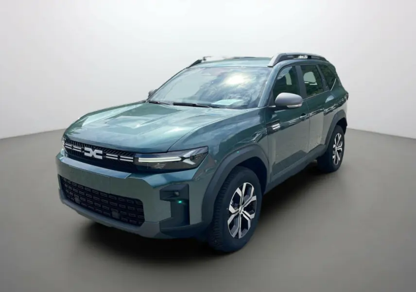 SUV Dacia Bigster vert cèdre en 3/4 avant droit, avec barres de toit et jantes alu 17 pouces visibles.