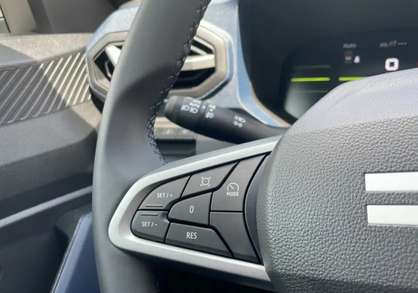 Gros plan sur le volant cuir du Dacia Bigster vert cèdre, mettant en valeur les commandes de régulateur de vitesse côté gauche.