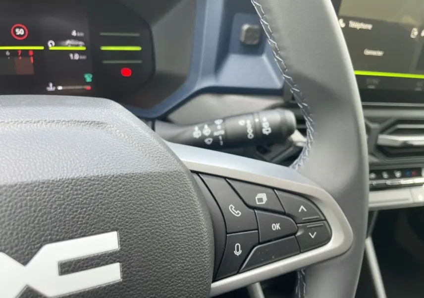 Gros plan sur le volant cuir du Dacia Bigster 2025, avec commandes multifonctions et tableau de bord numérique en arrière-plan.